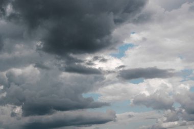 Açık ve koyu renkli bulutlar gökyüzünde ilginç şekiller oluştururlar; sadece birkaç yerde mavi gökyüzü görünür..