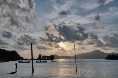 Sakin, ıssız bir sahilde bulutlu bir gün batımı..