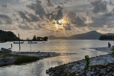 Sakin, ıssız bir sahilde bulutlu bir gün batımı..