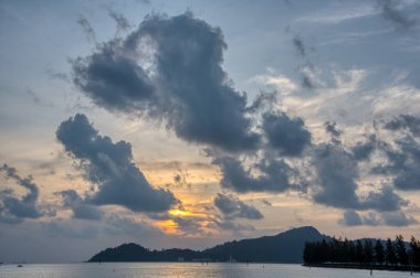 Sakin, ıssız bir sahilde bulutlu bir gün batımı..