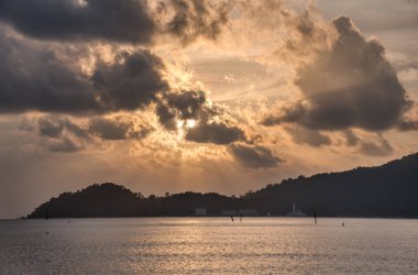 Sakin, ıssız bir sahilde bulutlu bir gün batımı..