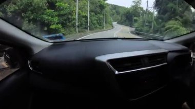 Perak, Malaysia. January 15,2023: Footage of the asphalt street in the countryside while driving in the interior and looking out the car front screen window along the Teluk Senangin to Lumut highway.