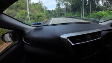 Perak, Malaysia. January 15,2023: Footage of the asphalt street in the countryside while driving in the interior and looking out the car front screen window along the Teluk Senangin to Lumut highway.