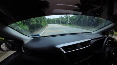 Perak, Malaysia. January 15,2023: Footage of the asphalt street in the countryside while driving in the interior and looking out the car front screen window along the Teluk Senangin to Lumut highway.