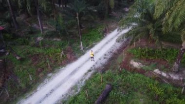 man taking quick shots mode with his drone at the pathway on the agriculture farmland 