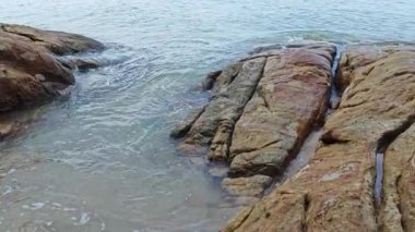 Kumlu sahil boyunca uzanan dev kayaların görüntüleri.   