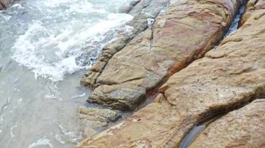 Kumlu sahil boyunca uzanan dev kayaların görüntüleri.   