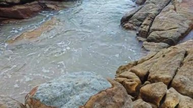Kumlu sahil boyunca uzanan dev kayaların görüntüleri.   