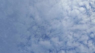 Sokakta sabahın erken saatlerinde elektrik direği boyunca mavi bulutlu gökyüzüne bakıyorum..