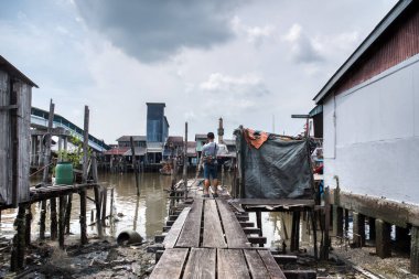 Sahildeki ahşap iskelede duran adam.