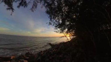 Gün batımında deniz suyunun dalgalanması kayalık sahile vuruyor..