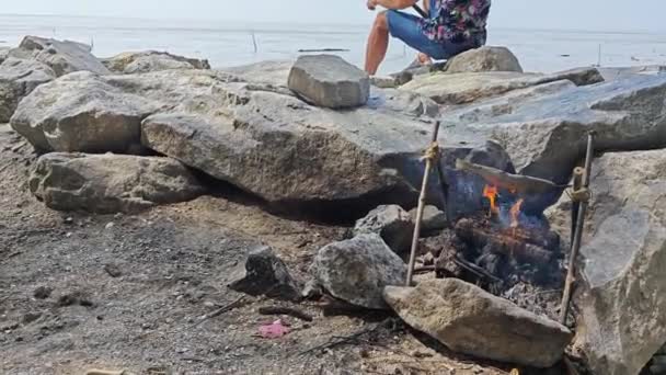 Mann Angelt Meer Während Fisch Holzfeuer Kocht — Stockvideo