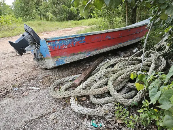 a coil of old nylon rope laying beside the wooden boat.