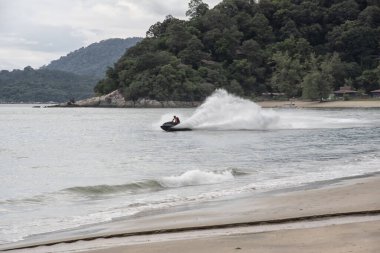 Bilinmeyen bir adam deniz kenarında jet ski kullanıyor..