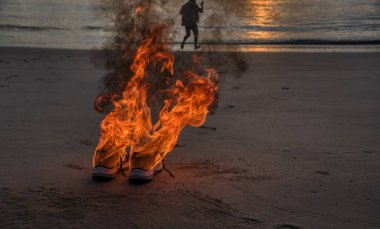Sahilde alevler içinde bırakılmış bir çift spor ayakkabı.