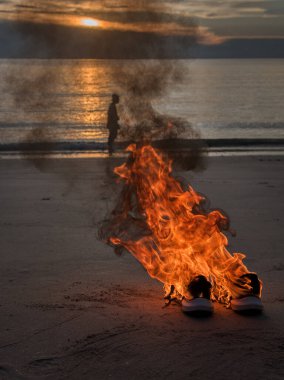 Sahilde alevler içinde bırakılmış bir çift spor ayakkabı.