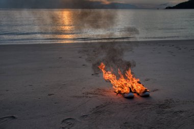 Sahilde alevler içinde bırakılmış bir çift spor ayakkabı.