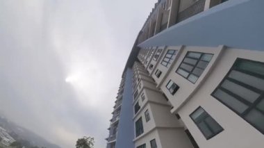 Ön plandaki gökdelen binası ile kasvetli gökyüzü arka planına bakıyorum..