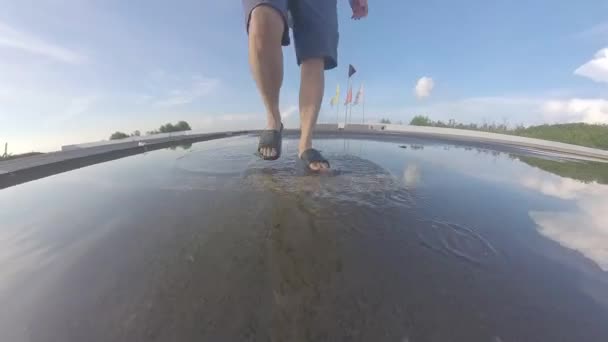 通りで停滞した雨水のプールを歩く男の足 — ストック動画