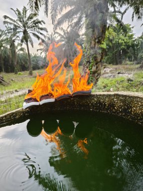 Silindirik beton kuyunun kenarından atılan eski ayakkabılar alevler içinde..