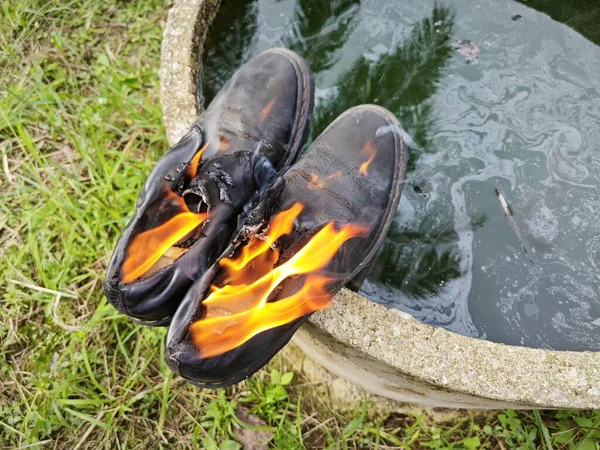 old thrown away shoes on flame by the edge of the cylindrical concrete well.