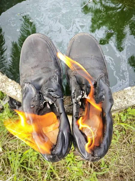 old thrown away shoes on flame by the edge of the cylindrical concrete well.
