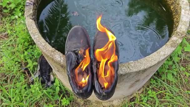旧鞋子在圆柱形混凝土井边的火焰中被丢弃 — 图库视频影像