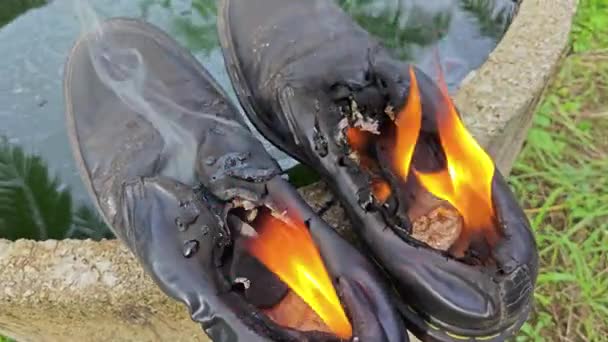 シリンダーコンクリートの端で炎の上に捨てられた古い靴はよく — ストック動画