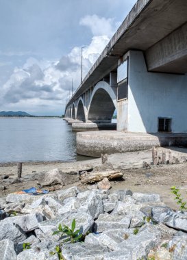 Beton köprü etrafında gündüz vakti olay yeri aktivitesi. 