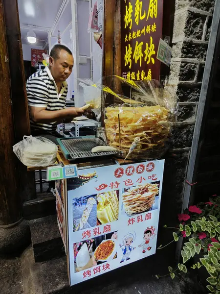 Dali, Çin, 20 Nisan 2024: Çin 'in Yunnan ilindeki Dali antik kentinde yiyecek ve ticaret malları arayan turistlerin yoğun caddelerin renkli gece manzarası