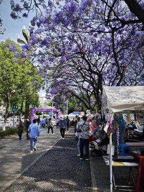 Yunnan, Çin. 26 Nisan 2024: Kunming kentsel iş caddesinde yürüyen insanların çevre şehri sahnesi.