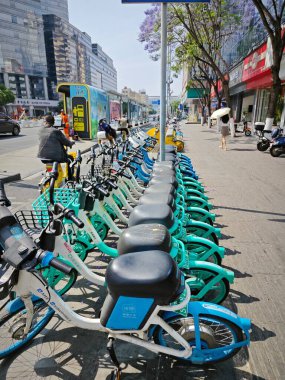 Yunnan, Çin. 26 Nisan 2024: Kunming kentsel iş caddesinde yürüyen insanların çevre şehri sahnesi.