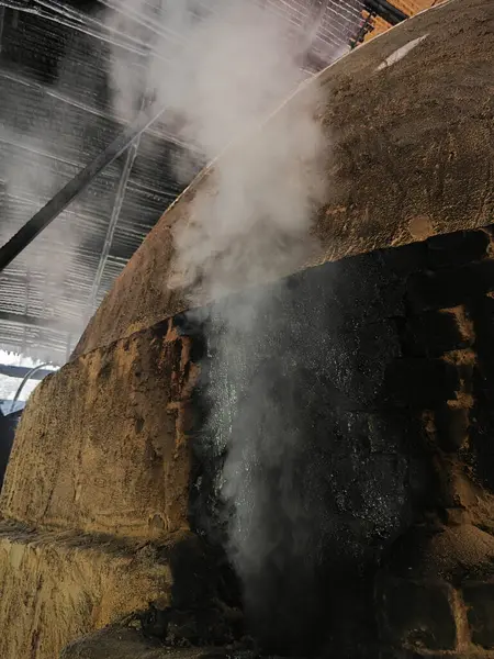 stock image bright smoke streaming from charcoal kiln outlet to the ceiling attap roof hole. 