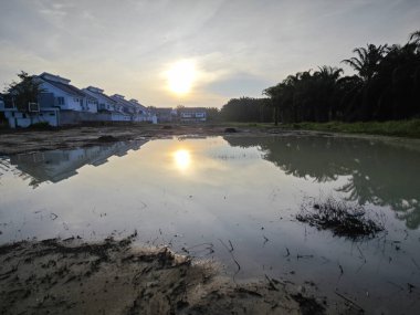 Yerleşim yerinin yakınındaki durgun çamurlu yağmur suyu havuzu boş görünüyor..