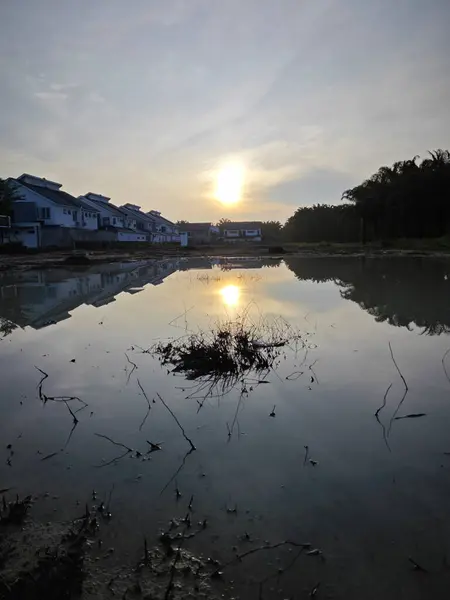 stock image scene of a vacant reflective pool of stagnant muddy rainwater land by the residential area.