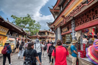 Yunnan, Çin. 30 Nisan 2024: Eski LiJiang kentindeki ünlü UNESCO antik kasaba mirasında turistlerin vitrinlere alışveriş yaptığı ve ticari mallar aradığı gündüz saatleri.