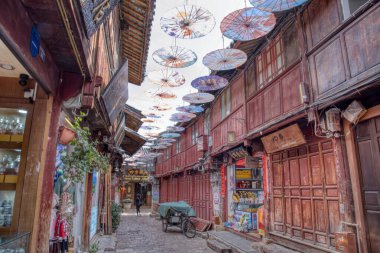 Yunnan, Çin. 30 Nisan 2024: Eski LiJiang kentindeki ünlü UNESCO antik kasaba mirasında turistlerin vitrinlere alışveriş yaptığı ve ticari mallar aradığı gündüz saatleri.