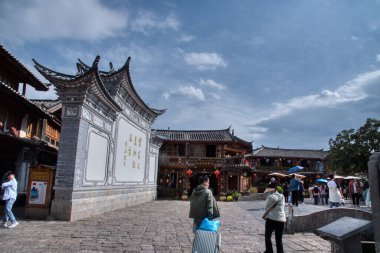 Yunnan, Çin. 30 Nisan 2024: Eski LiJiang kentindeki ünlü UNESCO antik kasaba mirasında turistlerin vitrinlere alışveriş yaptığı ve ticari mallar aradığı gündüz saatleri.