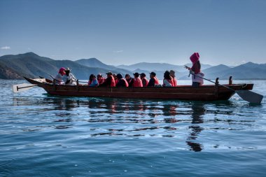 Yunnan,China. April 30,2024: Scene of activities on the lake and the pig-trough boats of Mosuo people around the beach at the Lugu Lake, Lijiang.  clipart