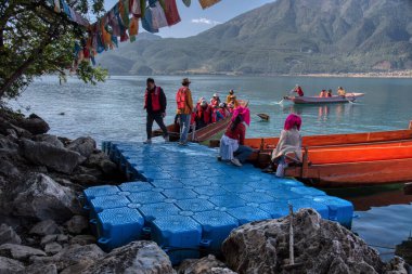 Yunnan,China. April 30,2024: Scene of activities on the lake and the pig-trough boats of Mosuo people around the beach at the Lugu Lake, Lijiang.  clipart
