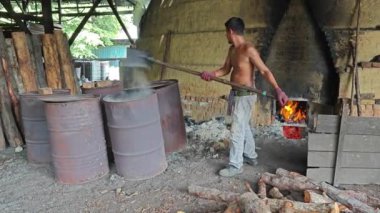 Perak, Malezya. 8 Mayıs 2024: Kelebung Kömür Fabrikası 'ndaki saf karbon üretimini ısıtan ocaktan kömür artığı kaldıran işçinin görüntüsü   