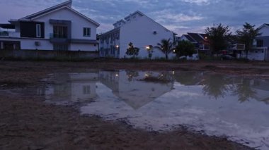 Sabahın erken saatlerinde yerleşim yerinin yanındaki durgun yağmur suyu havuzunda güneş doğuyor.. 