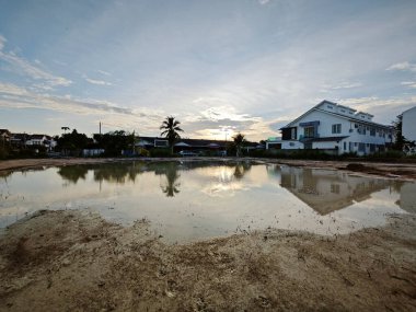 Yerleşim yerinin yakınındaki durgun çamurlu yağmur suyu havuzu boş görünüyor.. 