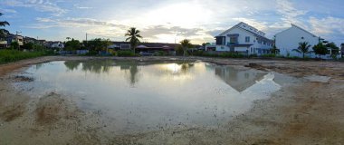 Yerleşim yerinin yakınındaki durgun çamurlu yağmur suyu havuzu boş görünüyor.. 