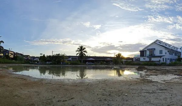 stock image scene of a vacant reflective pool of stagnant muddy rainwater land by the residential area. 