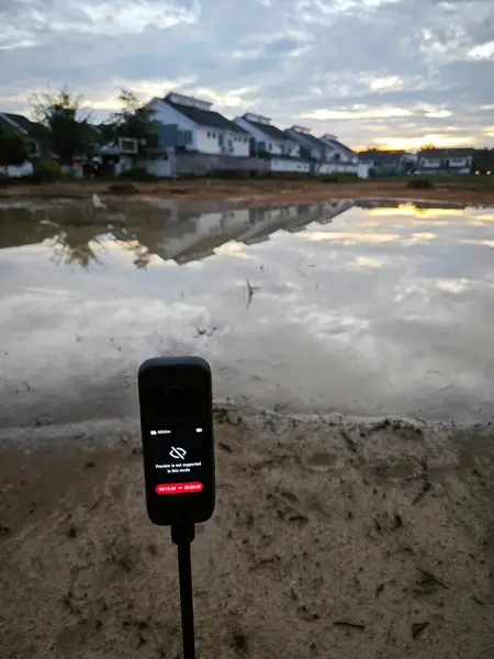 stock image Perak,Malaysia. June 10,2024: Scene of capturing footage using Insta360 device at the pool of water during the dawn hour at Taman Permai Vacant plot of land.