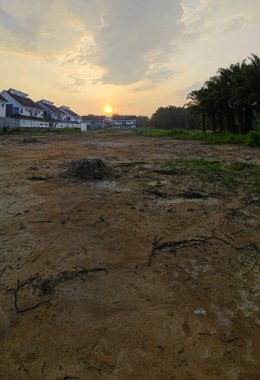 Boş arazinin çevresindeki renkli gökyüzüne bakıyorum..