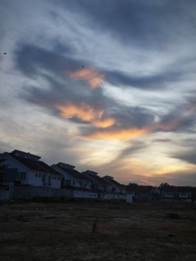 Boş arazinin çevresindeki renkli gökyüzüne bakıyorum..