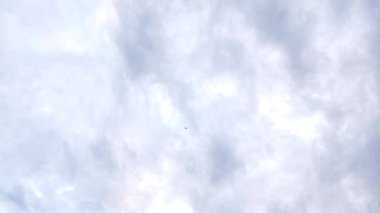 Mavi bulutlu gökyüzünde uçan bir uçağın uzaklık görüntüsü.