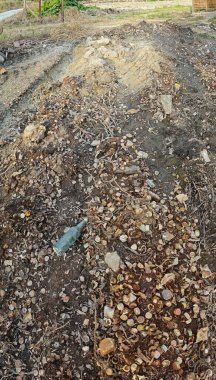 Çöpe atılmış, paslanmış ve çürümüş şişe kapaklarının panoramik görüntüsü.